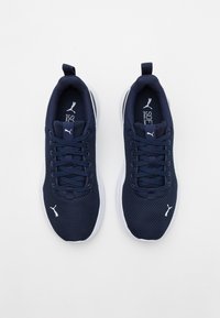 Chaussures de sport bleu marine avec empeigne en mesh, accents blancs, bout arrondi, lacets plats et col rembourré. Logo de la marque sur la languette et le côté.