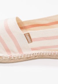 Espadrille shoe with a beige and light pink striped canvas upper, featuring a woven jute sole and a small brown label on the side.