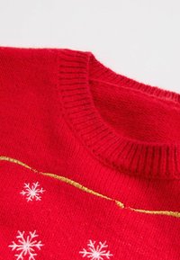 Maglione rosso lavorato a maglia con collo a coste, con motivi a fiocco di neve bianchi e una striscia orizzontale dorata sul petto.