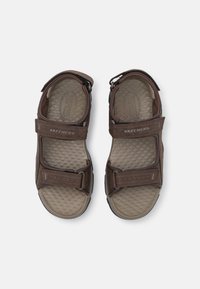 Brązowe syntetyczne sandały z regulowanymi paskami, teksturowaną wkładką i antypoślizgową podeszwą. Posiadają logo "Skechers" na górnych paskach.