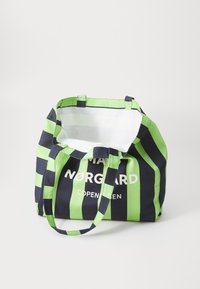 Borsa a strisce con tela blu scuro e verde brillante, interno bianco e manici lunghi fino alla spalla. Logo visibile sulla parte anteriore.