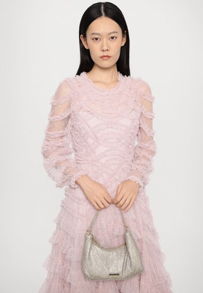 Zilveren metallic handtas met een gestructureerd, mesh ontwerp. Gepaard met een roze, geraffineerde jurk met transparante mouwen en gelaagd stof.