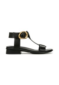 Sandal in pelle nera con design a T, hardware circolare dorato, tacco basso e superficie liscia.