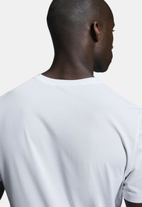 White performance t-shirt with a textured, breathable fabric; features a round neck and short sleeves, designed for athletic use.