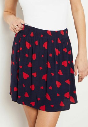 Jupe bleu marine avec imprimé cœurs rouges, taille élastique froncée, longueur genoux, tissu léger, texture lisse, style décontracté.