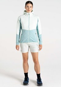 Leichte, kapuzenjacke mit einem weißen quilted Oberteil und einem himmelblauen Unterteil; kombiniert mit hellen Shorts und schwarzen Socken sowie blauen Schuhen.