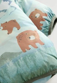 Couverture en coton avec un fond bleu clair ornée d'ours bruns illustrés. Bordée de passepoil vert et dotée d'une finition texturée et douce.