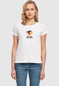 Hvid bomulds t-shirt med korte ærmer, der har et grafisk tryk af en fodbold og teksten "WIR SAGEN DANKE SCHÖN" i sort og rød.