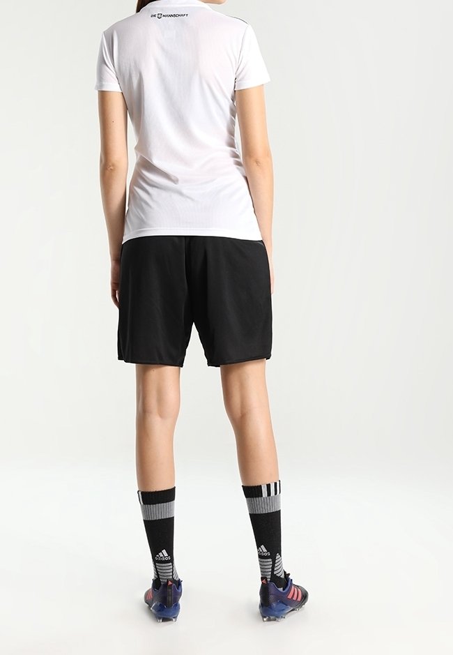 Camisa blanca de manga corta, pantalones cortos negros, calcetines a rayas negras y grises, botas azul y negra, logo en la parte trasera de la camisa, diseño atlético y deportivo.