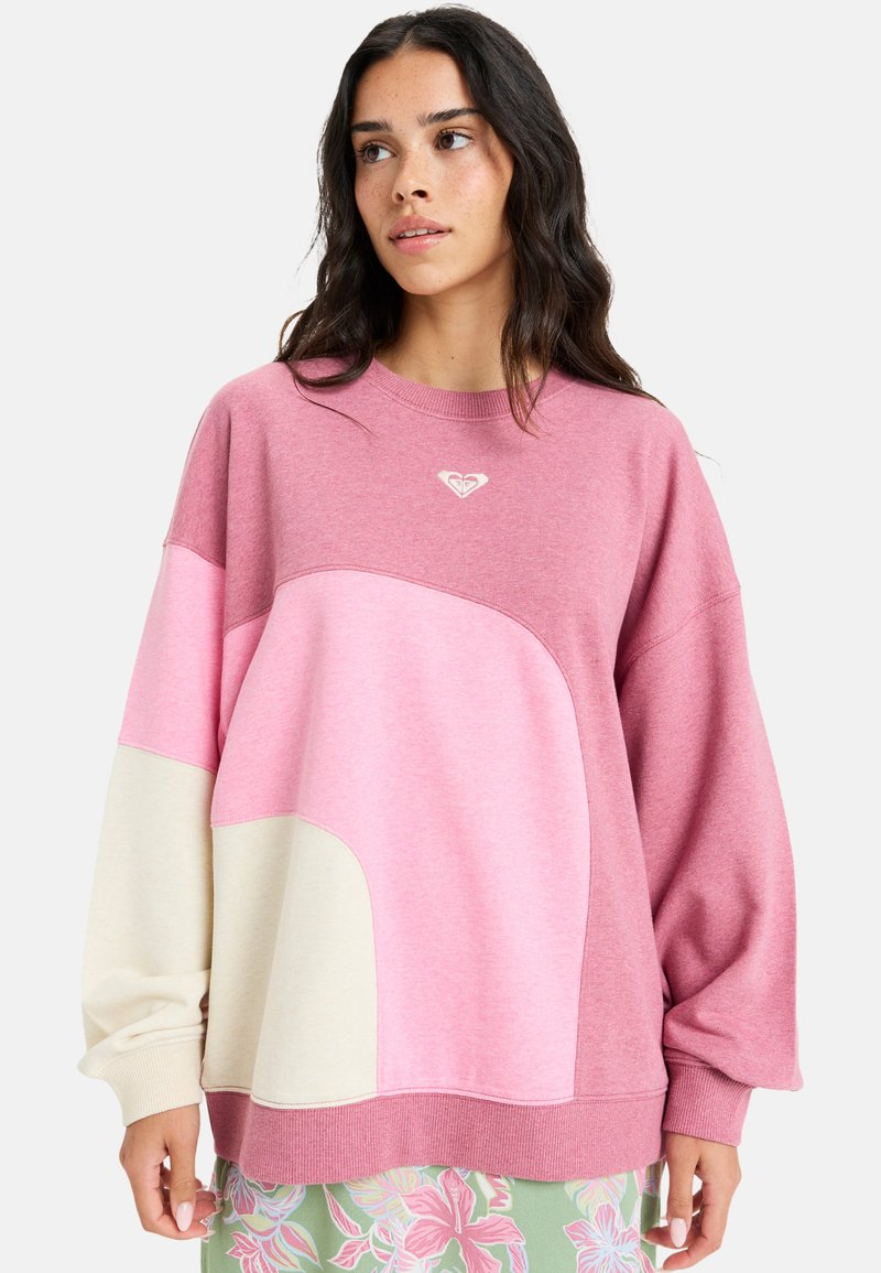 Sweatshirt i pink og creme, med farveblokdesign og rund form. Fremstillet af blødt stof, med et lille logo på brystet.