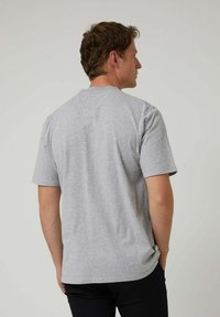 Camiseta de algodón gris con mangas cortas, cuello redondo y un corte relajado. Textura suave sin patrones ni acentos visibles.