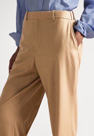 Μπεζ παντελόνι με tailored κοπή και λεία υφή, με πλαϊνές τσέπες και ίσια γραμμή στα πόδια. Συνδυασμένο με ανοιχτό γαλάζιο πουκάμισο.