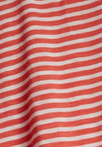 Červenobíle pruhovaná látka s hladkým povrchem, obsahující rovnoměrně rozložené vodorovné čáry a měkký, elastický materiál.