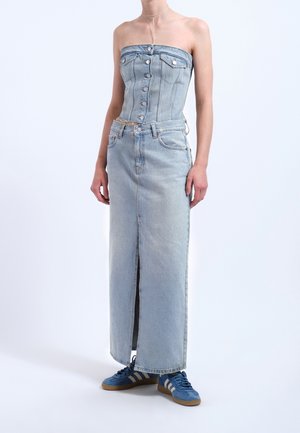 Person wearing light blue strapless denim corset top and matching long denim skirt with front slit, paired with blue sneakers.
