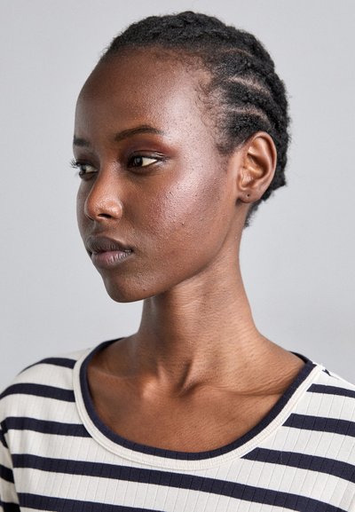 Striped ribbed top featuring a wide neckline, in cream with navy stripes. Close-cropped hair and smooth skin; no visible jewelry.