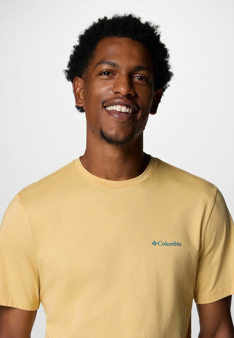 Gelbes Baumwoll-T-Shirt mit Rundhalsausschnitt und kurzen Ärmeln, versehen mit einem kleinen blauen Logo auf der linken Brust. Glatte Textur.