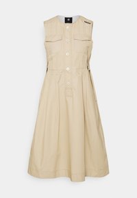 Beige värinen hihaton mekko puuvillasekoitetta, jossa kaksi rintataskua, napitettava etuosa ja liehuva helma.