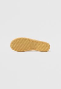 Rubber outsole with a textured surface, featuring horizontal and vertical grooves, in a light brown color, designed for grip and durability.