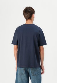 Dunkelblauses Baumwoll-T-Shirt mit kurzen Ärmeln, rundem Ausschnitt und geradem Schnitt. Der Stoff wirkt weich und hat eine glatte Textur.