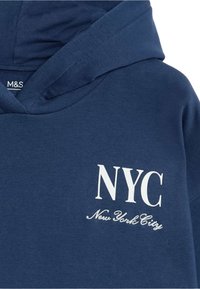 Sudadera navy con bolsillo canguro y estampado de texto en blanco: "NYC" y "New York City". El material parece suave con una textura lisa.