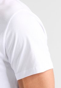 Witte katoenen t-shirt met een ronde halslijn en korte mouwen. Glad textuur, basisontwerp, met een rechte zoom en schone randen.