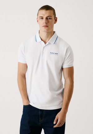 Maglietta polo bianca con dettagli blu sul colletto, presenta un logo Red Bull Racing sul petto, maniche corte e vestibilità standard.