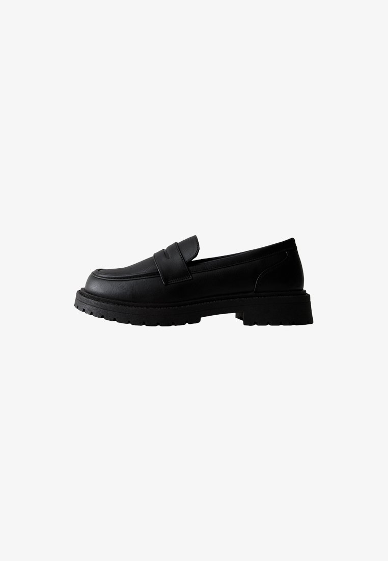 Mocassins en cuir noir avec un bout arrondi, deux sangles à l'avant et une semelle épaisse et texturée. Finition lisse et mate.