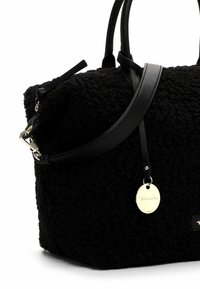 Must tekstuuriga käekott, millel on pehme kangast keha, siledad nahkrihmad ja kuldse tooni metallist sildiga logo.