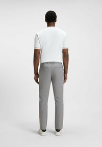 Pantalon gris ajusté, associé à un haut blanc à manches courtes. La vue de dos montre des poches plaquées et une finition en tissu lisse.