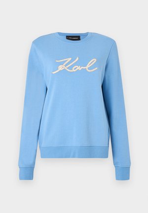 Ανοιχτό μπλε φούτερ με μακριά μανίκια, ριμπ μανσέτες και τελείωμα, με το όνομα "Karl" γραμμένο σε στυλ σκοινιού στο στήθος.