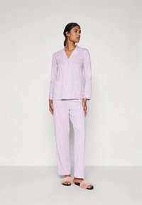 Σετ πυτζάμες ανοιχτό μωβ με ρίγες που περιλαμβάνει τοπ με κουμπιά και μακριά μανίκια, καθώς και παντελόνι ίσιας γραμμής. Μαλακό ύφασμα με άνετη εφαρμογή.