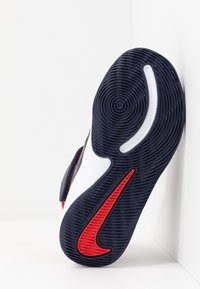 Musta-valkoinen urheilukenkiä pohja punaisilla korostuksilla. Ominaisuuksiin kuuluu teksturoitu pinta, jossa on pyöreitä kuvioita ja näkyvä swoosh-logo.