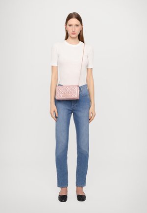 Borsa a tracolla rosa trapuntata con catena, caratterizzata da una forma rettangolare e un motivo stampato, esposta con jeans in denim e una camicia bianca.