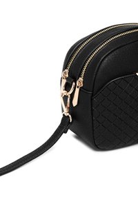 Schwarze Handtasche aus synthetischem Leder mit gestepptem Muster, doppelte goldene Reißverschlüsse und einem dünnen Tragegurt mit abnehmbarem Verschluss. Quadratdesign, kompakte Größe.