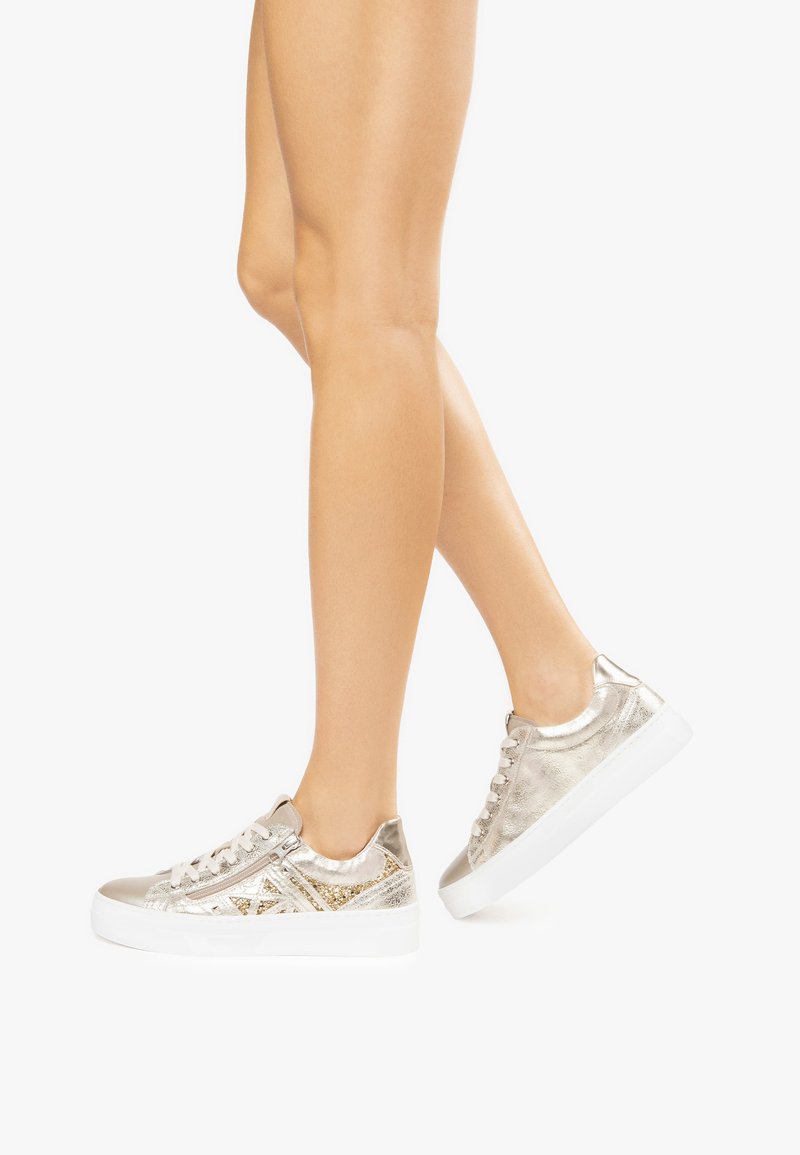 Zapatillas plateadas metálicas con acabado texturizado, con diseño de cordones y suela de goma blanca, con acentos decorativos en los laterales.