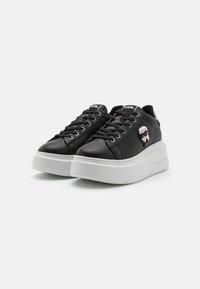 Sorte lær-lave sneakers med en hvid platformsål, med snørebånd, en markant logoaccent og syninger.