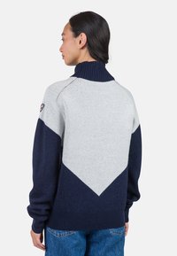 Strickpullover mit hohem Rippkragen, grauen und marineblauen Farbblöcken sowie einem Zickzackmuster auf der Rückseite. Weiche Textur und lässige Passform.