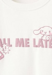 Hvid sweatshirt med prægede lyserøde bogstaver "CALL ME LATER" og en tegneserie-kanin. Glat tekstur og rund halsudskæring.