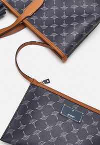 Czarna skórzana torebka i sakiewka z beżowymi akcentami, z powtarzającym się szarym wzorem emblematów oraz złotymi detalami na sakiewce.