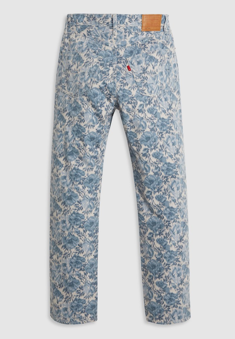 Jean à motif floral dans une palette de couleurs bleu clair et crème, présentant une coupe droite, des poches arrière et une pièce en cuir sur la ceinture.
