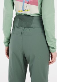 Groene skibroek met een hoge taille, voorzien van een gestructureerde elastische band, een soepele stof en een discreet logo aan de zijkant.