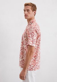 Korte mouwen, overhemd met kraag in crèmekleur met een rood bloemenpatroon, gemaakt van lichtgewicht stof. Voorzien van knopen en een relaxte pasvorm.