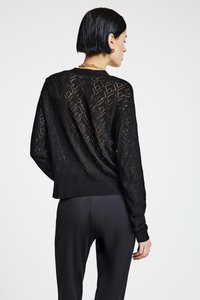 Schwarzer, gestrickter Pullover mit Diamantmuster, lockerer Passform, rundem Ausschnitt und geripptem Saum. Über schwarzen Hosen getragen, zeigt ein gekürztes Design.