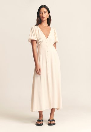 Light beige, midi-length dress with a deep V-neck, puff sleeves, and front button detailing. Smooth fabric, layered skirt, and simple design.