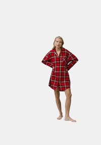 Abito camicia a scacchi rossi in un tessuto leggero, dotato di una chiusura con bottoni frontale, maniche lunghe e una tasca sul petto.