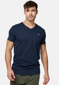 Marineblå v-hals t-shirt lavet af bomuld, med korte ærmer og et diskret logo på brystet. Glat tekstur med en tætsiddende pasform.