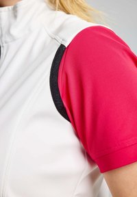 Sportliches Kurzarmoberteil mit weißem Hauptteil, leuchtend pinken Ärmeln, schwarzen Akzenten und strukturiertem Stoff. Reißverschluss am Kragen vorhanden.