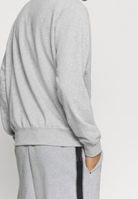 Grå sweatshirt med en avslappnad passform, tillverkad av mjukt material, med ribbad nederkant och muddar, kombinerad med matchande sweatpants som har sidofickor.