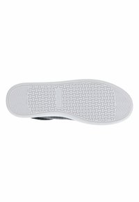Black shoe sole with a textured white rubber outsole featuring a patterned grip, logo detail, and a rounded toe shape.