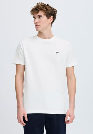 Vit bomullströja med rund halsringning och korta ärmar. Har en liten svart logotyp på vänster bröst. Minimalistisk design.